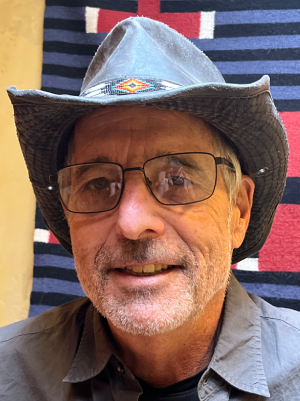 Portrait of Daniel Fiverson wearing cowboy hat, blu, black, red, white geometric pattern blanket behind him