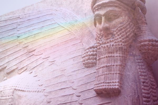 Photograph of ancient Sumerian statue of bearded god with wings, rainbow prism