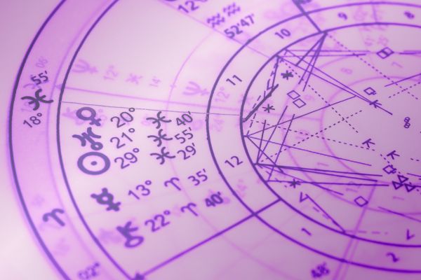 Close-up photograph of a portion of an Astrology chart in shades of Kepler College purple, with glyohs showing Venus, Uranus and the Sun conjunct in Pisces, Mercury in Aries, aspect lines