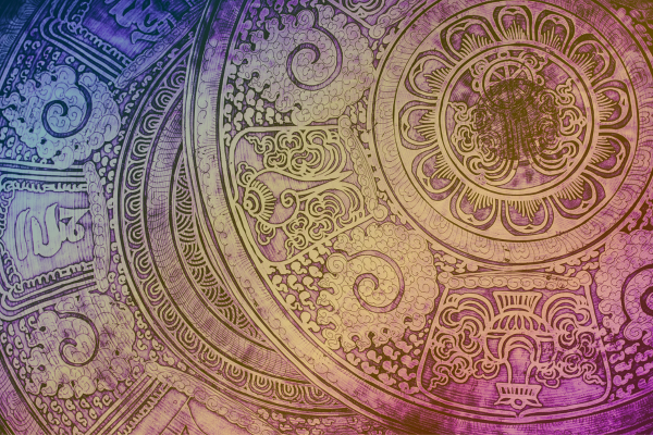 Photograph of metal engraving with Tibetan style art and zodiac wheel references, shades of Kepler College purple, magenta, and gold